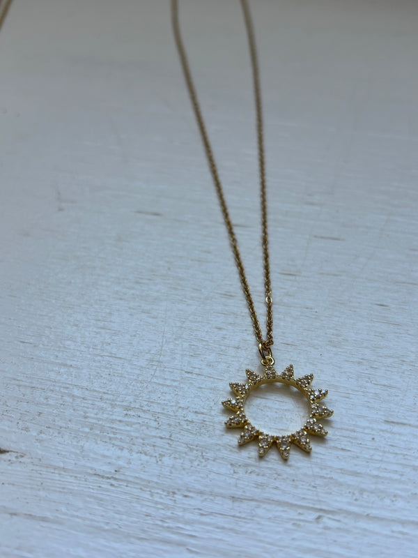 Gold-plated sunburst pendant necklace with crystal embellishments on an 18-inch gold chain. A radiant, celestial-inspired jewelry piece.