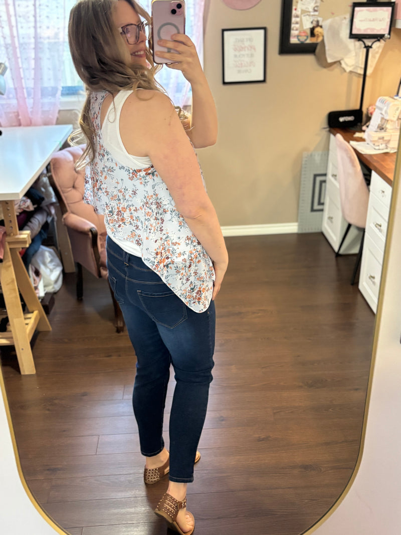 Woman wearing a lightweight blue floral vest over a white tank top and jeans, showcasing a stylish and versatile layering piece