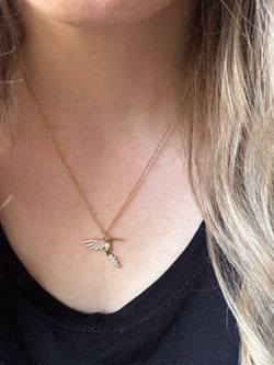 Gold-plated hummingbird pendant necklace with crystal details on an 18-inch stainless steel pvd coated gold chain, worn by a person. A delicate and symbolic nature-inspired jewelry piece