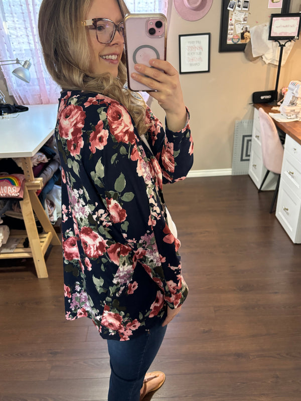 A soft, flowy dolman sleeve cardigan with a delicate floral pattern, draped over a model. The lightweight fabric gives it an airy, relaxed fit, making it a versatile layering piece. Designed to fit sizes 2 to 16, this cardigan features a flattering silhouette with an open front. Perfect for casual or dressy outfits, the breathable material ensures comfort in all seasons.