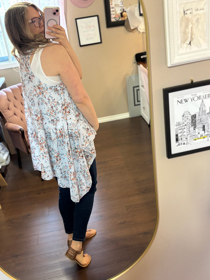 Woman wearing a lightweight blue floral vest over a white tank top and jeans, showcasing a stylish and versatile layering piece