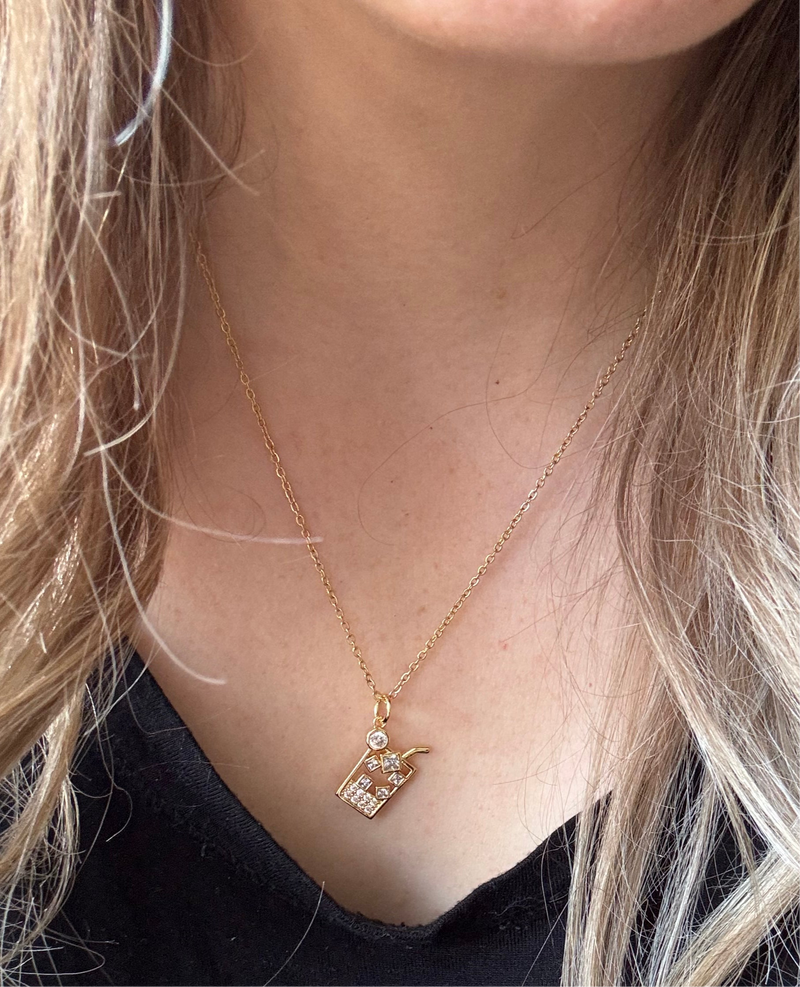Gold-plated iced drink pendant necklace with crystal ice cube details on an 18-inch stainless steel pvd coated gold chain, displayed on a women’s neck. A fun and trendy jewelry piece.