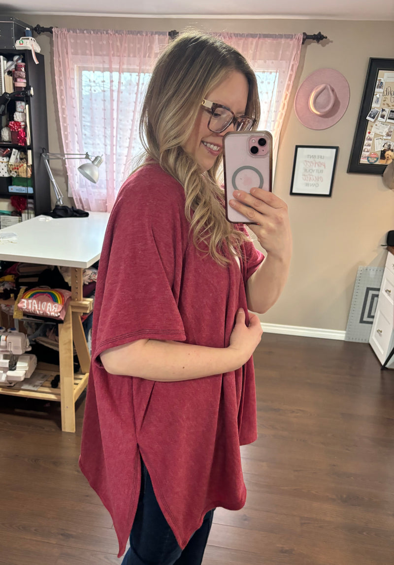 Model wearing a red/pink kimono cardigan over a white tank top and jeans, standing in a stylish home studio