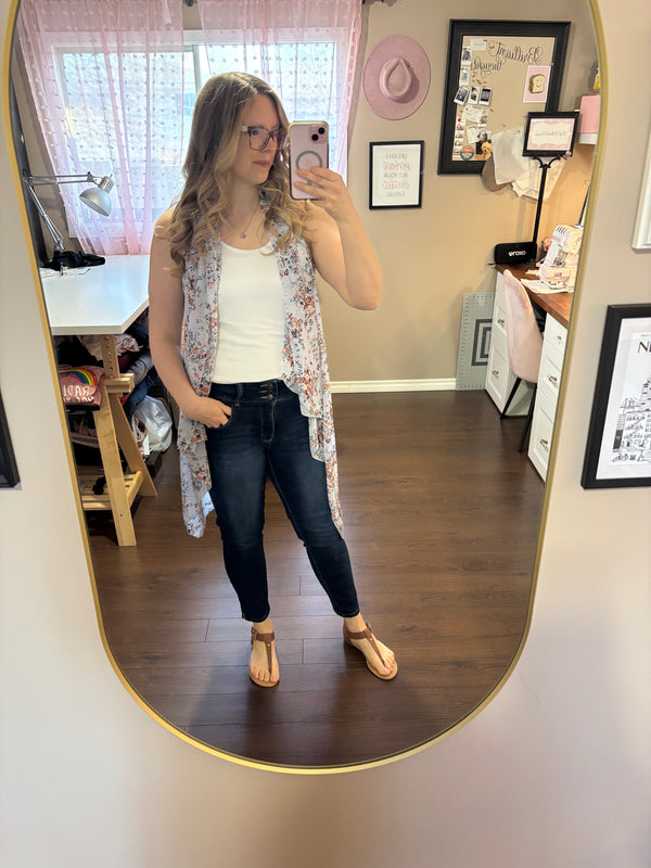 Woman wearing a lightweight blue floral vest over a white tank top and jeans, showcasing a stylish and versatile layering piece