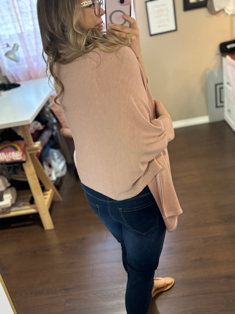 Smiling woman taking a mirror selfie while wearing a pink City Shrug over a white tank top and dark jeans, paired with casual sandals.